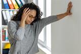 Woman clutching wall feeling dizzy